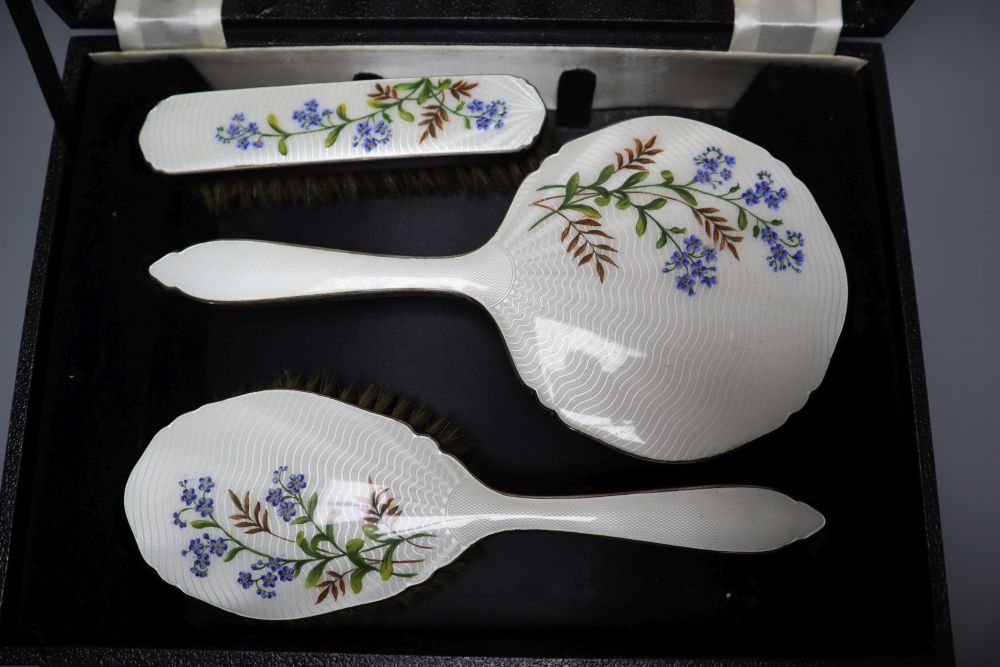 A three piece silver plated translucent enamelled dressing table set, cased